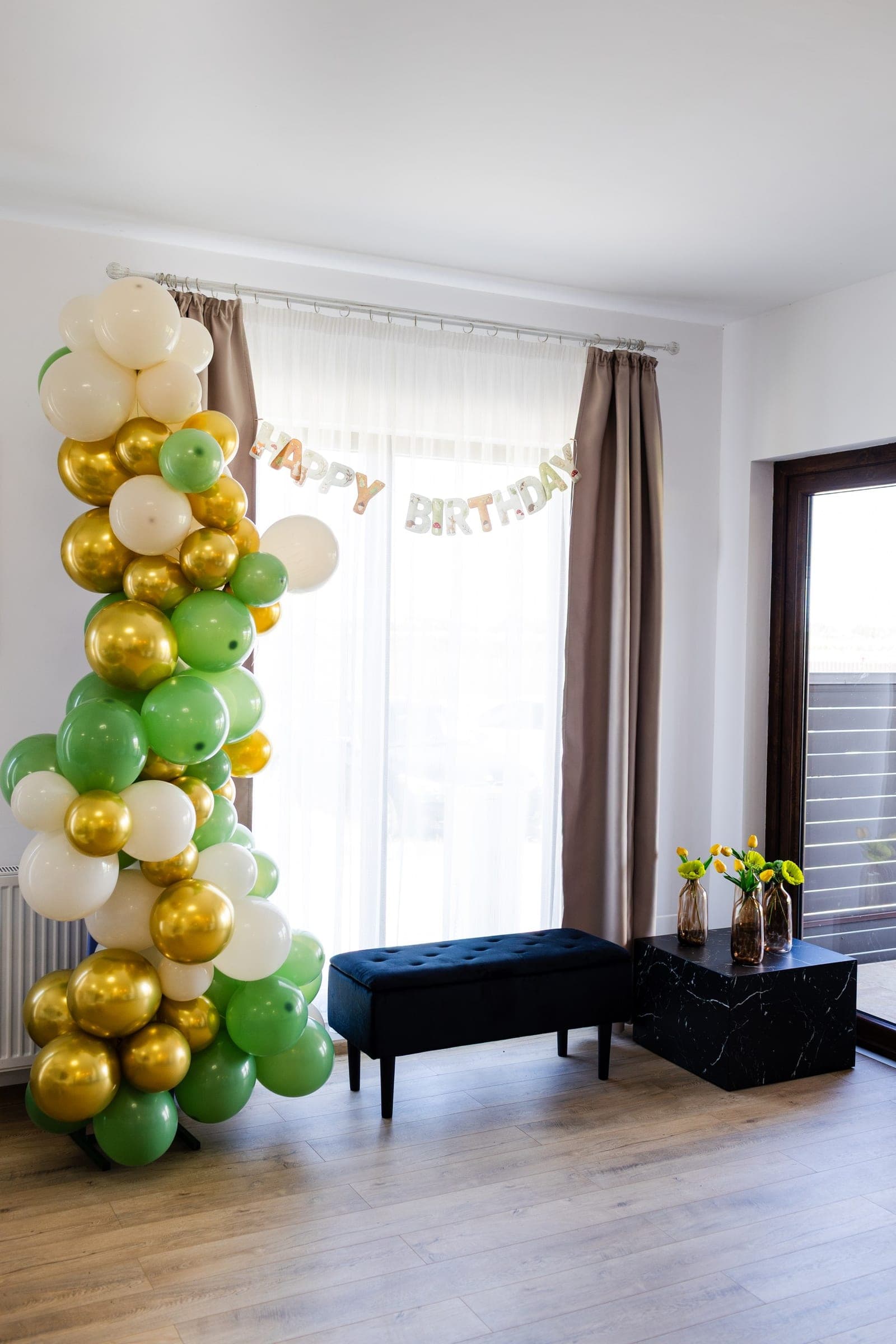 Colț foto cu arcadă de baloane verzi, albe și aurii și banner Happy Birthday